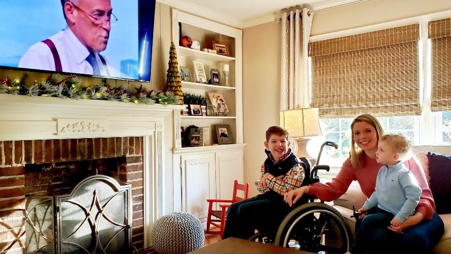 Child with cerebral palsy and his family watch a local weatherman on TV