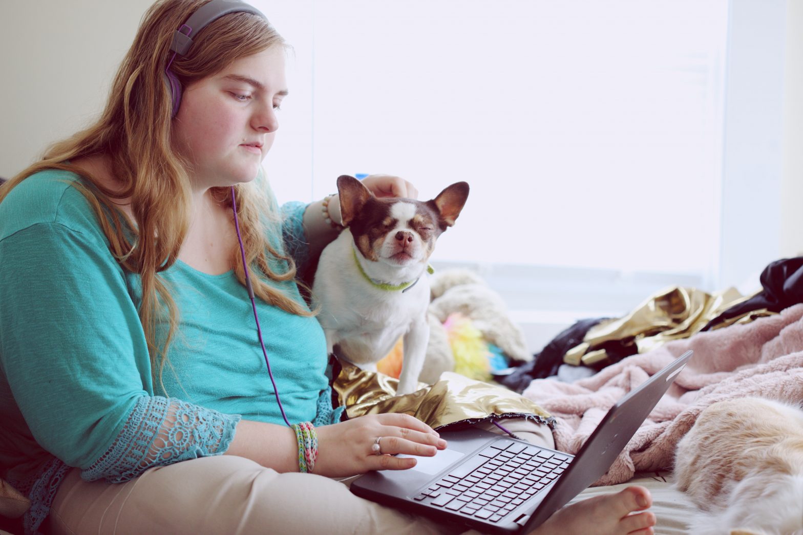 Young woman with service dog wearing headphones and looking at computer